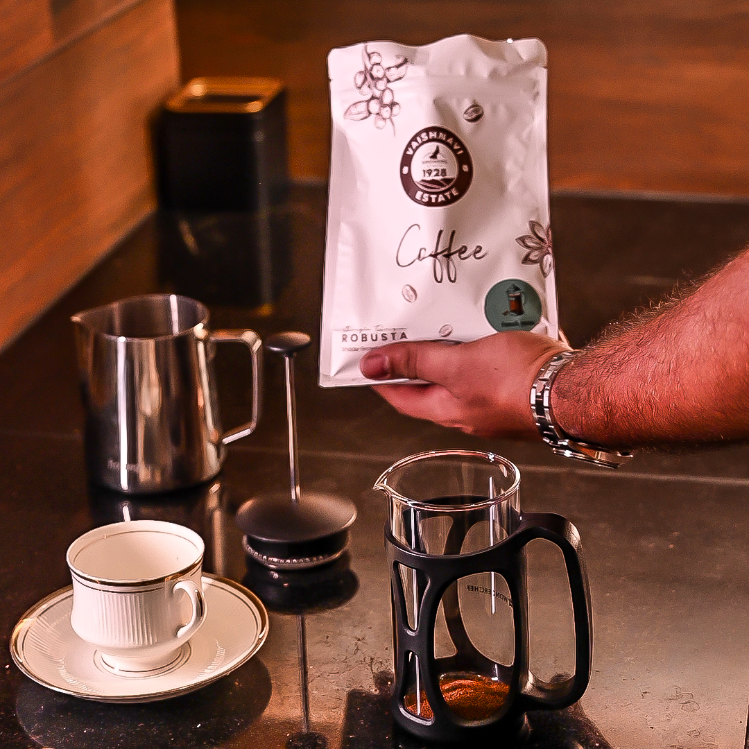 Person holding a Vaishavi Estate coffee bag with brewing equipment on a counter